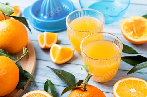 Visualização: Espremedor de frutas e laranjas frescas maduras em tampo de mesa de madeira azul