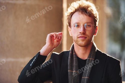 Preview: Portrait of elegant young man in glasses and formal classy clothes outdoors in the city