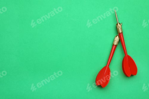 Preview: Red dart arrows on green background, flat lay with space for text
