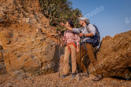 Preview: Tourists show helping young woman with backpacks hike on rocky top mountain trekking and soft foggy