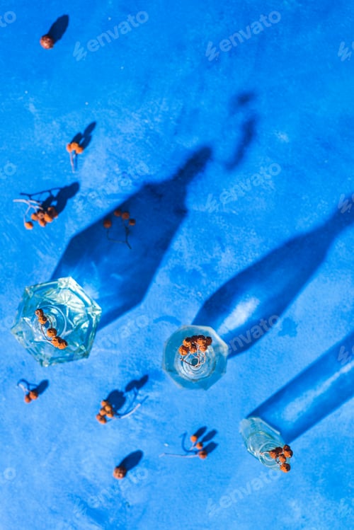 Preview: Glass bottle pattern with dried leaves and berries on a blue background with shadows and flares