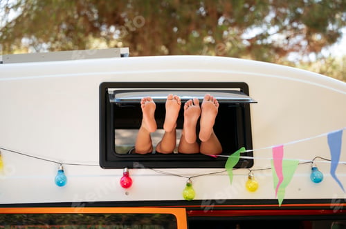 Preview: The children's feet stick out the window of the van on a wonderful day of camping. Vanlife concept.