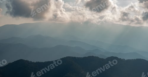 Preview: Mountain landscape with bright sun rays shining and cloudy sky in the morning.
