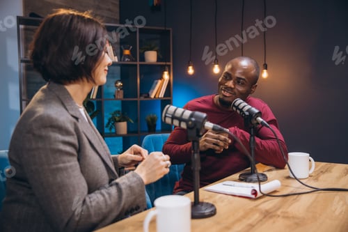 Preview: Podcasters engaging in lively conversation during a dynamic live recording session in modern studio