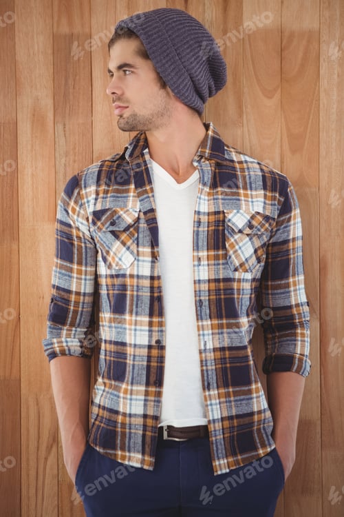 Preview: Confident hipster looking away while standing against wooden wall