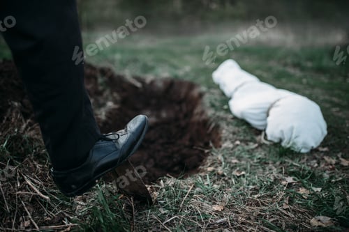 Preview: Male murderer with a shovel is digging a grave