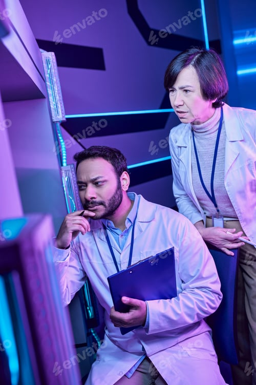 Preview: Hindu Male and Adult Female Scientists Gaze Mysteriously at Computer in Neon-Lit Science Center