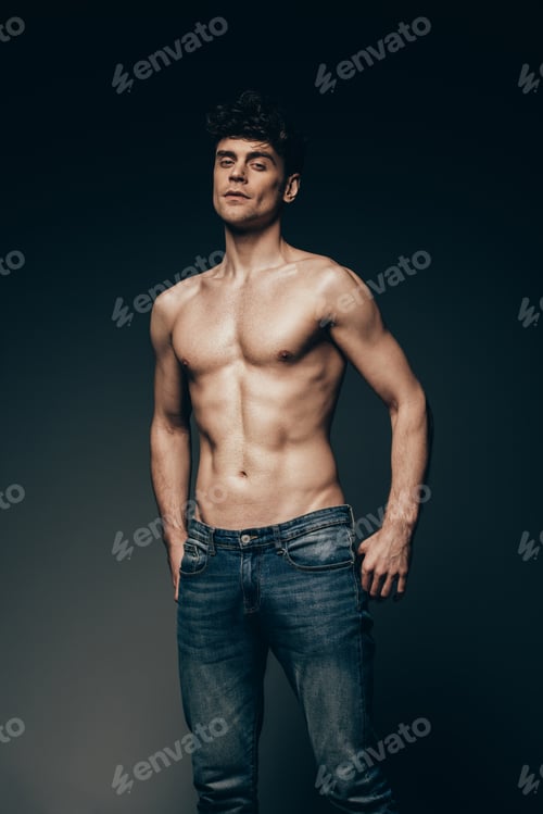 Preview: sexy macho in jeans posing isolated on dark grey