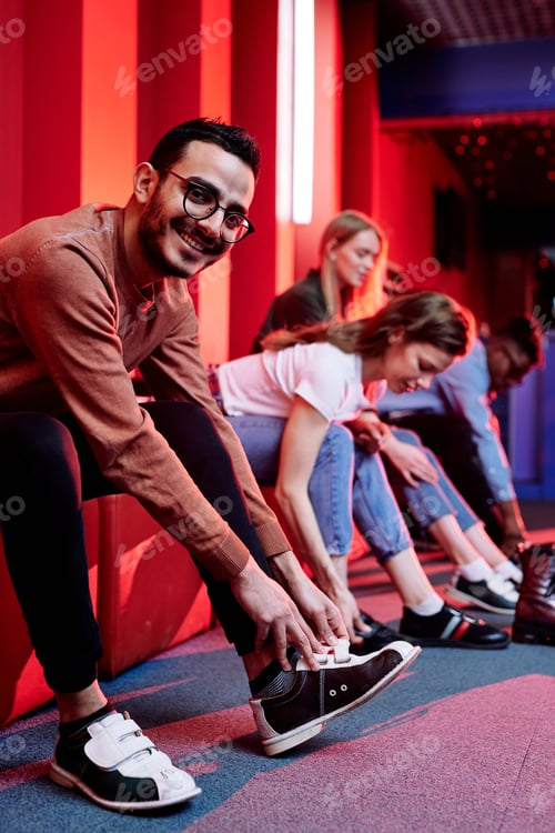 Preview: Happy young man and his friends on background getting ready to play bowling