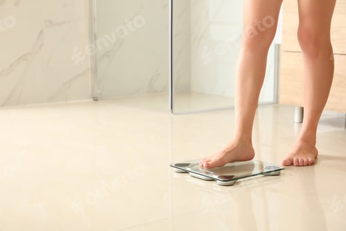 Preview: Woman stepping on floor scales in bathroom, space for text. Overweight problem