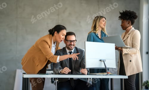 Preview: Senior business manager talking with experienced colleague while using computer in office.