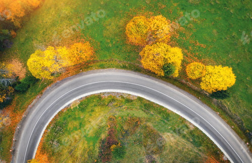 Preview: Aerial view of winding road in autumn forest at sunset