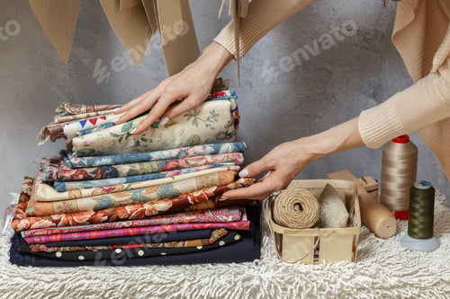 Preview: Woman hands choosing fabric In sewing atelier. Sewing accessories and fabric in small home workshop