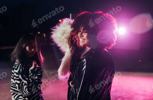 Preview: Small group of girls standing together at night near pink light