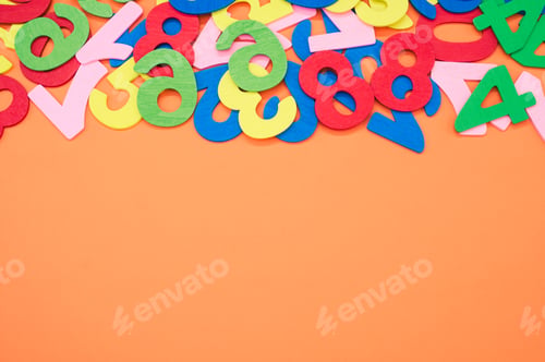 Preview: Closeup shot of the colorful wooden numbers scattered on an orange surface - space for text