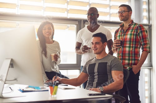 Preview: Relaxed young workers around computer in office