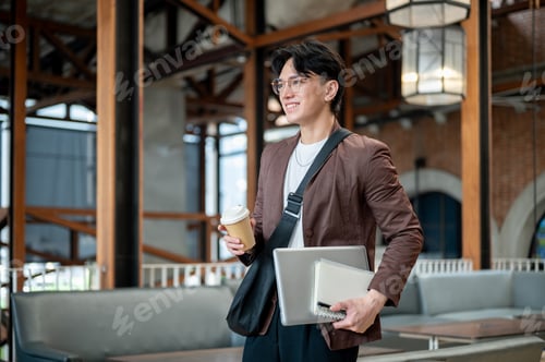 Preview: Brown suit man with glasses walking while holding a coffee cup with notebook and laptop the in cafe.