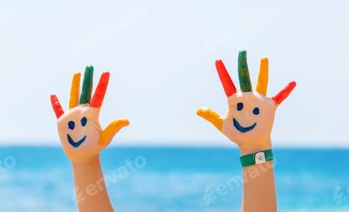 Preview: On the hands of the child, a smile with paints on the sea. Selective focus.