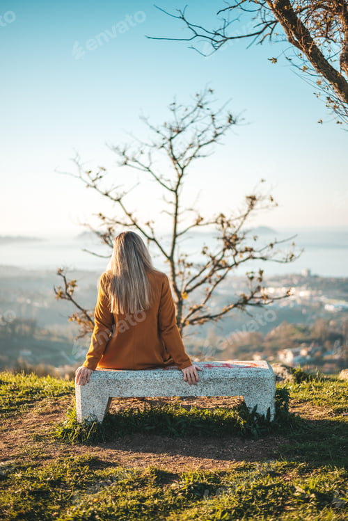 Preview: Woman on a yellow coat contemplating the landscape