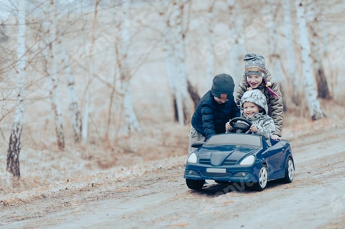 Preview: Three happy children playing with big old toy car in countryside, outdoors.