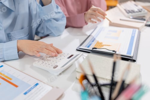 Preview: Two female colleagues discussing business reports together in a modern office environment