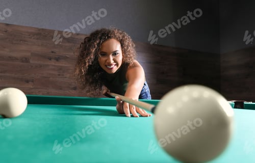 Preview: Young African-American woman playing Russian billiard indoors