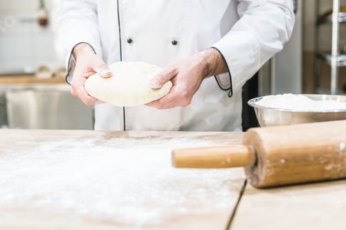 Preview: Baker holding uncooked dough in hands
