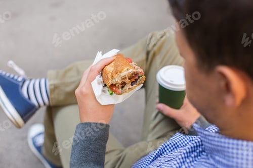 Preview: Smiling man having lunch sitting in the bench