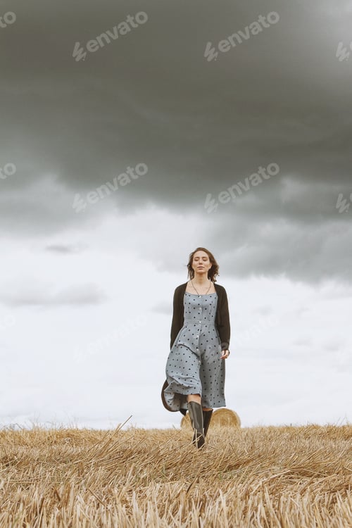Preview: Woman Walks across a Farm Field Under Cloudy Sky