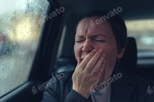 Preview: Tired exhausted businesswoman yawning at taxi vehicle back seat on her way home from work