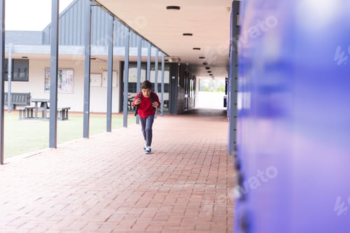 Preview: In school, young biracial boy is running along a corridor outdoors