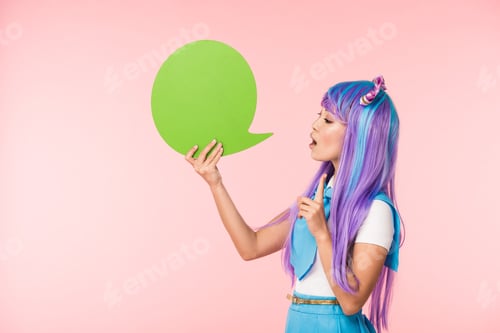 Preview: Asian anime girl holding green speech bubble and showing idea sign on pink
