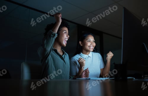 Preview: Shot of two young businesswomen cheering while using a computer during a late night at work