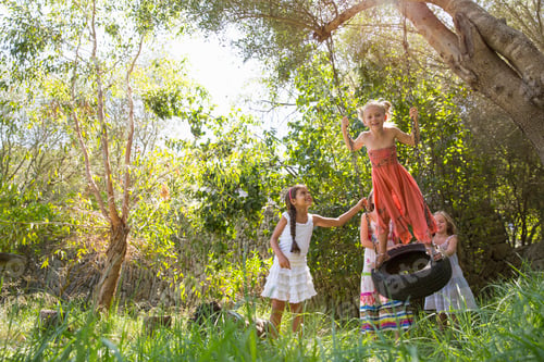 Preview: Four girls playing on tree tire swing in garden