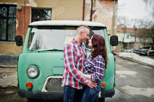 Preview: Stylish couple wear on checkered shirt in love together against old minivan.