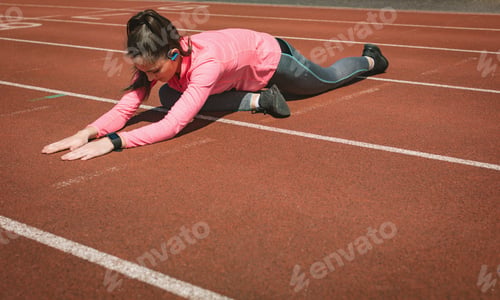 Preview: Woman performing stretching exercise on a race track