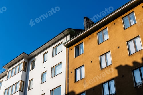 Preview: Sunlit facades of Helsinki buildings painted gold and white stand against a clear sky.