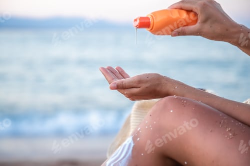 Preview: A woman applies sunscreen on the beach. close up