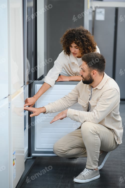 Preview: Couple choosing refrigerator in electronics store examining home appliances
