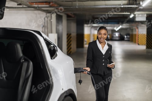 Preview: Professional with smartphone filling up EV in parking garage
