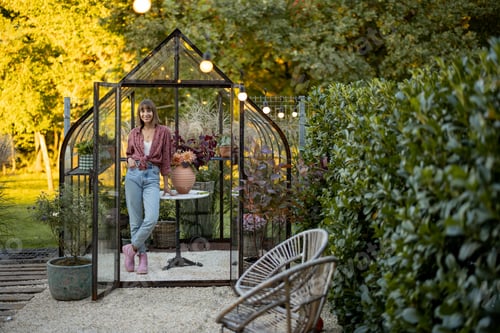 Preview: Woman near greenhouse with flowers at back yard