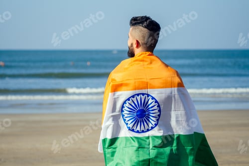 Preview: Indian young man waving indian tricolour flag outdoor near beach