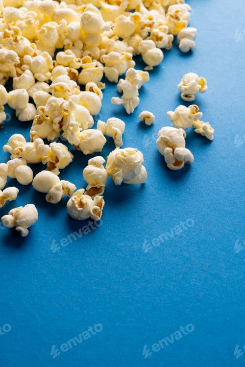 Preview: Vertical image of pop corn scattered on blue surface