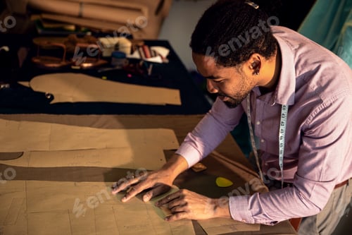 Preview: Male fashion tailor working on the measurements for the suit design in his workshop.
