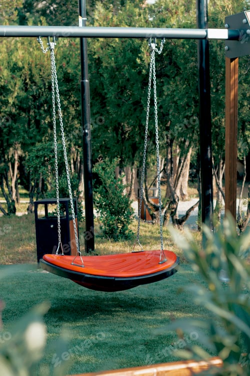 Preview: Unique hanging swing in a lush green garden during a sunny day with trees in the background