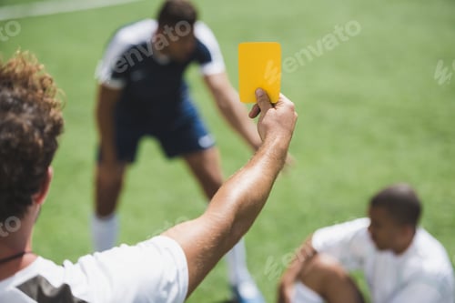 Preview: back view of soccer referee showing yellow card to players during game