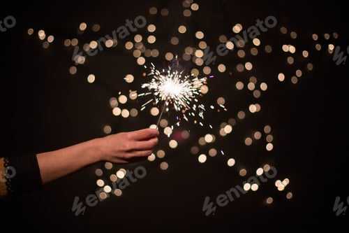 Preview: A young woman holds a sparkler and a gift in her hands. Christmas and New Year. Celebration concept