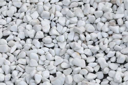 Preview: A lot of round and oval stones of white color lie on the ground in the garden