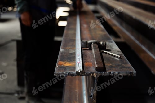 Preview: Hammer and measuring tape laying on steel in warehouse