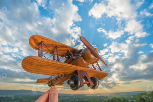 Preview: The hand hold wooden plane on the background of a blue sky